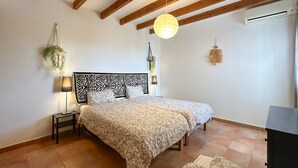 A bedroom with a bed, bedside lamps, a hanging plant, and a ceiling fan. - Villa Hugo Cómpeta by Ruralidays (Málaga)