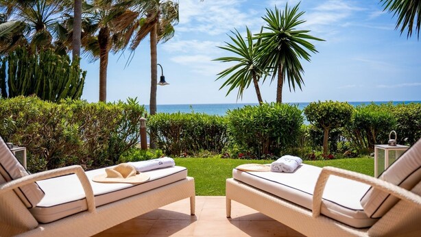 Two sun loungers with towels, a lamp, and a view of the ocean.