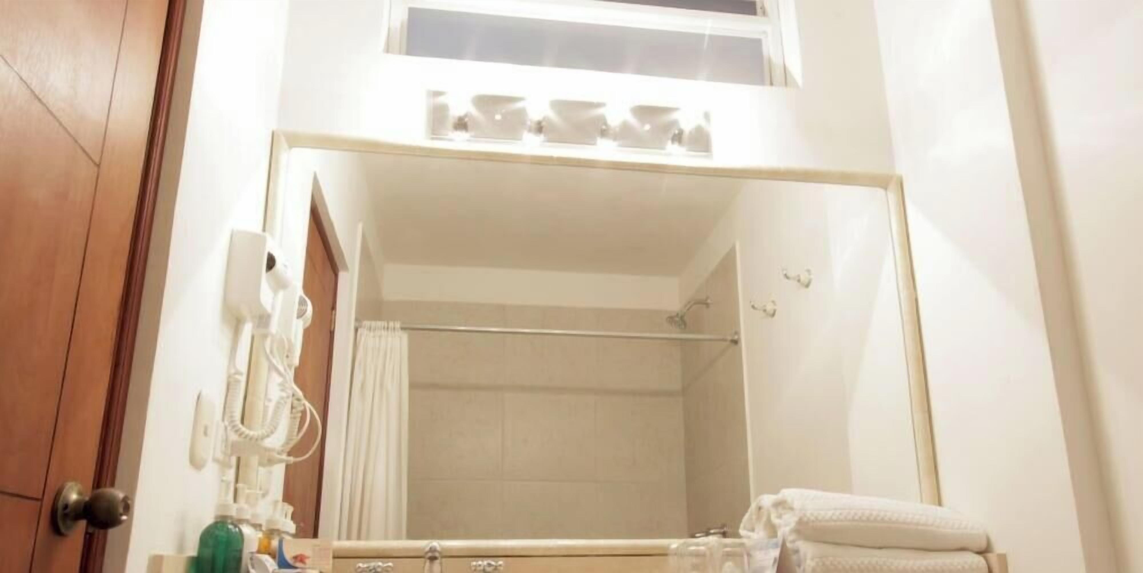 A bathroom with a large mirror, a towel rack, a shower curtain, and a sink with toiletries.