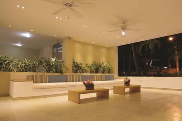 A spacious lobby with a low ceiling, recessed lighting, and two ceiling fans. There are potted plants along the walls and a reception desk. - Tamaca Torre Norte Hotel by Sercotel Hotels (Santa Marta)