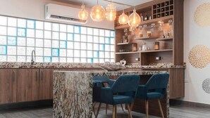 Een moderne keuken met een marmeren eiland, blauwe stoelen, houten kastjes en hangende verlichting.