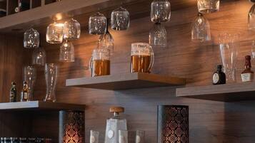 A bar area with shelves holding various glassware and bottles, including beer mugs and liquor bottles.