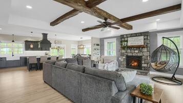 A spacious living area with a large gray sectional sofa, a stone fireplace, and a hanging chair.