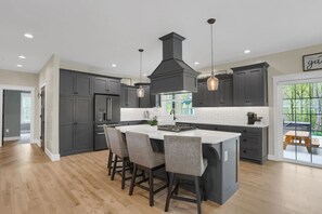 Una cocina moderna con una isla central, armarios oscuros e iluminación colgante.