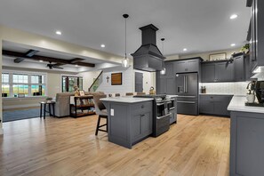 A modern kitchen with grey cabinetry, a central island, and a dining area with a sofa and books.
