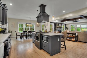 A modern kitchen with a central island, built-in appliances, and a dining area with a view of the outdoors.
