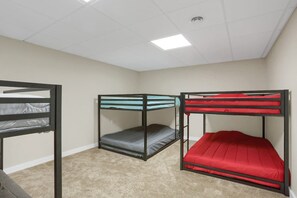 A room with bunk beds, carpeted floor, and a white ceiling with lights.
