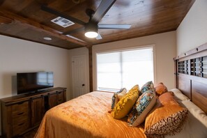 A bedroom with a bed, a television on a wooden dresser, a ceiling fan, and a window with blinds. - Estate Home Overlooking The Vineyard (Santa Fe)