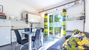 Una cocina moderna con comedor, sofá y vistas al exterior a través de un ventanal corredero.