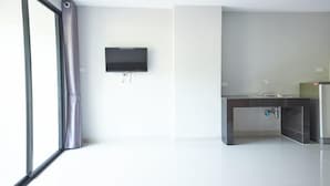 A modern kitchen with a built-in sink, a flat-screen TV mounted on the wall, and a large window with curtains. - Baan Pakdi (Pattaya)