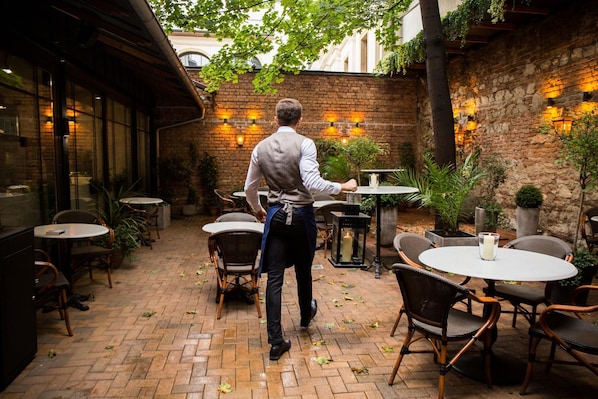 A brick patio with outdoor seating, tables, and chairs. - Balthazar Design Hotel (Kraków)