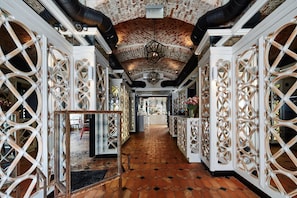A corridor with ornate white lattice partitions, a brick ceiling, and a tiled floor. - Balthazar Design Hotel (Kraków)