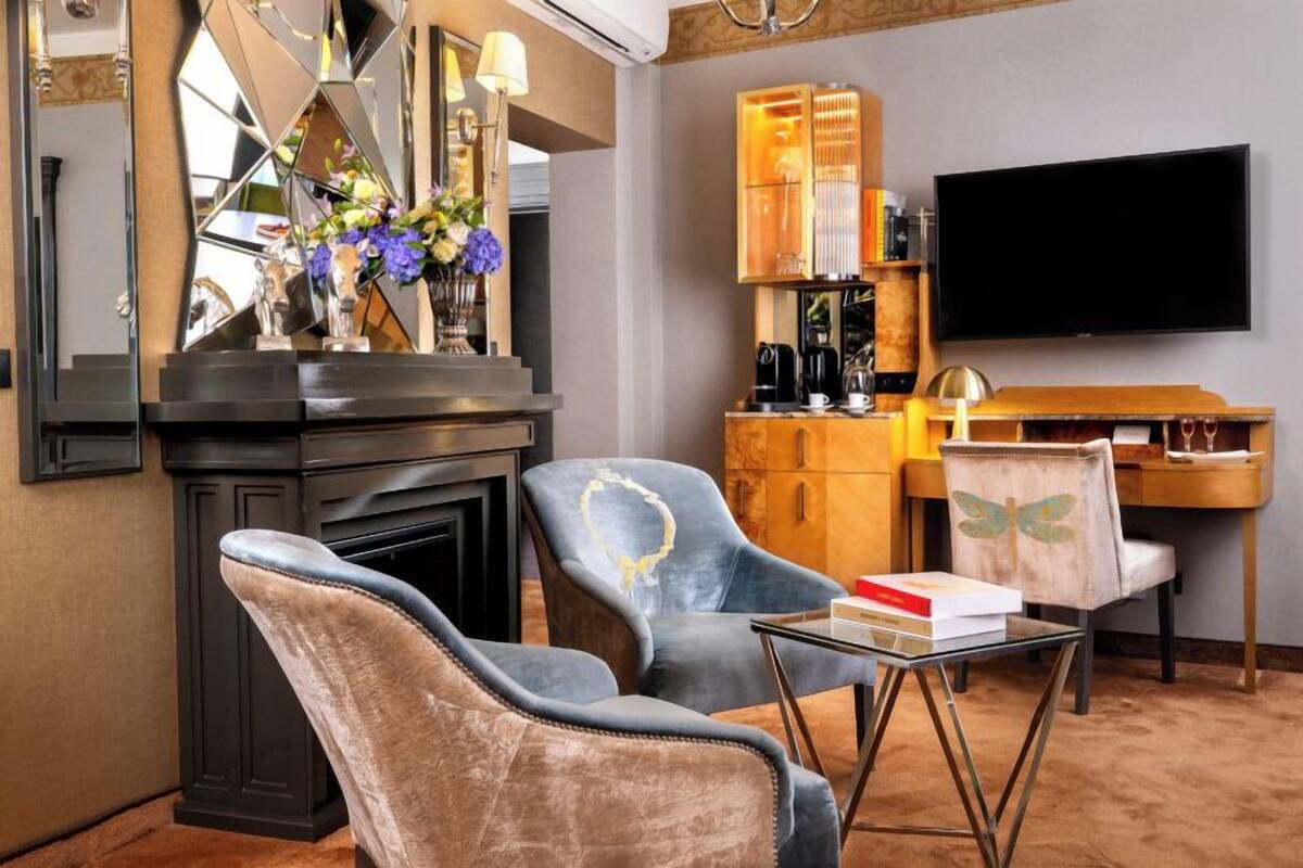 A modern living room with a fireplace, two armchairs, a coffee table, and a TV.