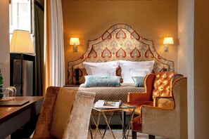 A hotel room with a large bed, two bedside lamps, a chair, a small table, and a window with curtains. - Balthazar Design Hotel (Kraków)
