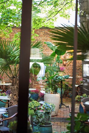 An outdoor seating area with brick walls, potted plants, and tables. - Balthazar Design Hotel (Kraków)