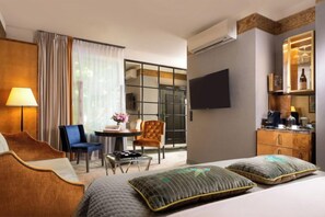 A hotel room with a bed, a desk, a chair, a TV, and a minibar. - Balthazar Design Hotel (Kraków)
