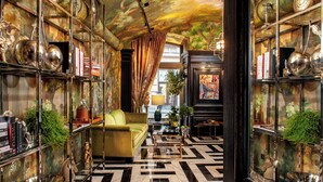 A room with a patterned floor, a green sofa, and shelves with decorative items. - Balthazar Design Hotel (Kraków)