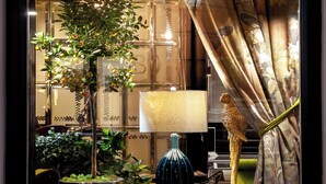A room with a large window, a potted plant, a lamp, and a curtain. - Balthazar Design Hotel (Kraków)