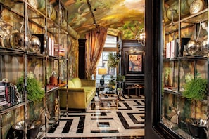 A room with a patterned floor, a green sofa, and shelves with decorative items. - Balthazar Design Hotel (Kraków)