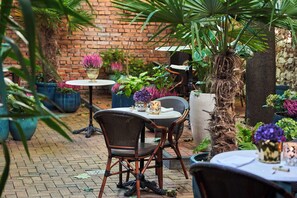 An outdoor patio with brick walls, potted plants, and wicker chairs. - Balthazar Design Hotel (Kraków)