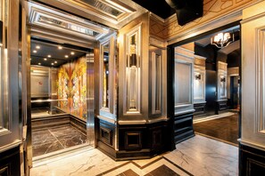 Un hall d’entrée luxueux, doté d’un sol en marbre, de boiseries décoratives et d’un lustre.