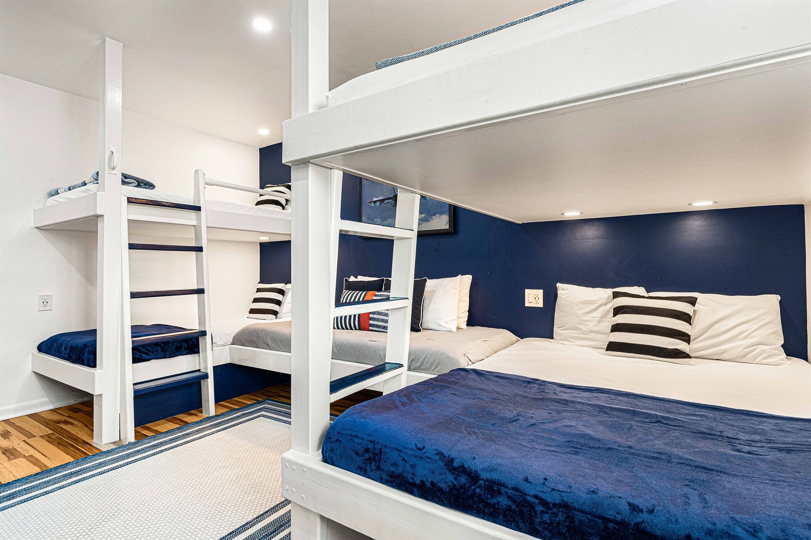 Habitación con literas, un colchón azul, literas blancas y una ventana con una ilustración.