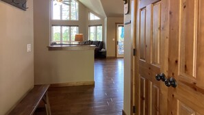 A spacious hallway with wooden flooring, a built-in bench, and a door with a rustic design. - Gt254 Goat Trail Lookout (Whitefish)
