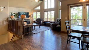 A spacious living area with a high ceiling, large windows, and a dining area with a table and chairs. - Gt254 Goat Trail Lookout (Whitefish)