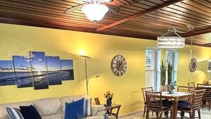 A living room with a sofa, coffee table, and dining area with chairs and a table. - Beachfront Paradise w/ King Room, Pool, Hot Tub! (South Padre Island)