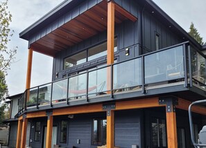 A modern two-story house with a balcony, large windows, and a wooden deck. - PRIVATE Hot Tub with Valley Views!! (Colwood)