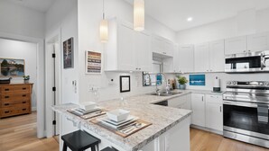 A modern kitchen with white cabinets, a granite countertop, stainless steel appliances, and pendant lighting. - PRIVATE Hot Tub with Valley Views!! (Colwood)