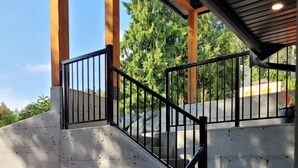 A concrete staircase with black railings leading to a covered area with wooden beams. - PRIVATE Hot Tub with Valley Views!! (Colwood)