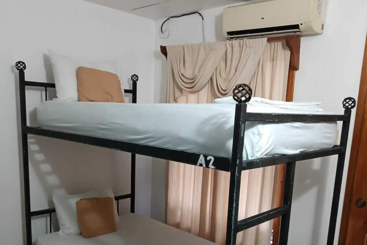 A bunk bed with a mattress labeled "A2" in a room with tiled flooring and an air conditioning unit on the wall.