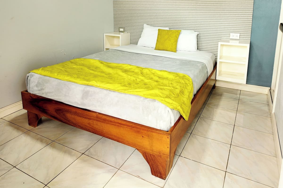 A bed with a wooden frame, a headboard, and a yellow blanket.