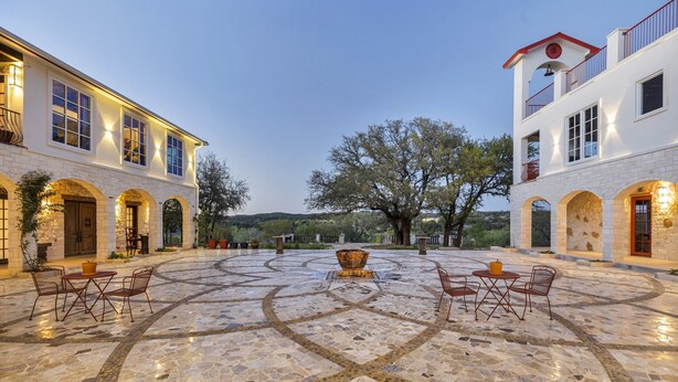 A spacious courtyard with a tiled floor, outdoor seating, and a large central fountain. - A perfect destination for lovers of excellence and fine art (Spicewood)