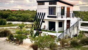 Una casa moderna de dues plantes amb un balcó, una escala i vistes a un riu.