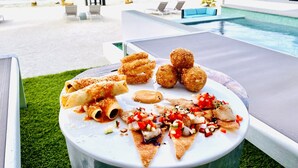 Taula de menjador amb plat de menjar, piscina i vista a la platja.