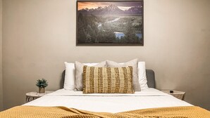 Ein Schlafzimmer mit Bett, Bergblick und einer kleinen Pflanze auf dem Nachttisch.