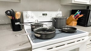 Eine Küche mit einem weißen Herd, Töpfen, Pfannen und einem Küchenutensilienhalter.