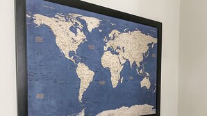 Eine gerahmte Weltkarte an einer weißen Wand.