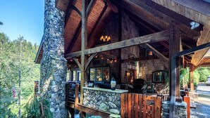 Una cabaña rústica con paredes de piedra, vigas de madera y un patio cubierto con mobiliario exterior.