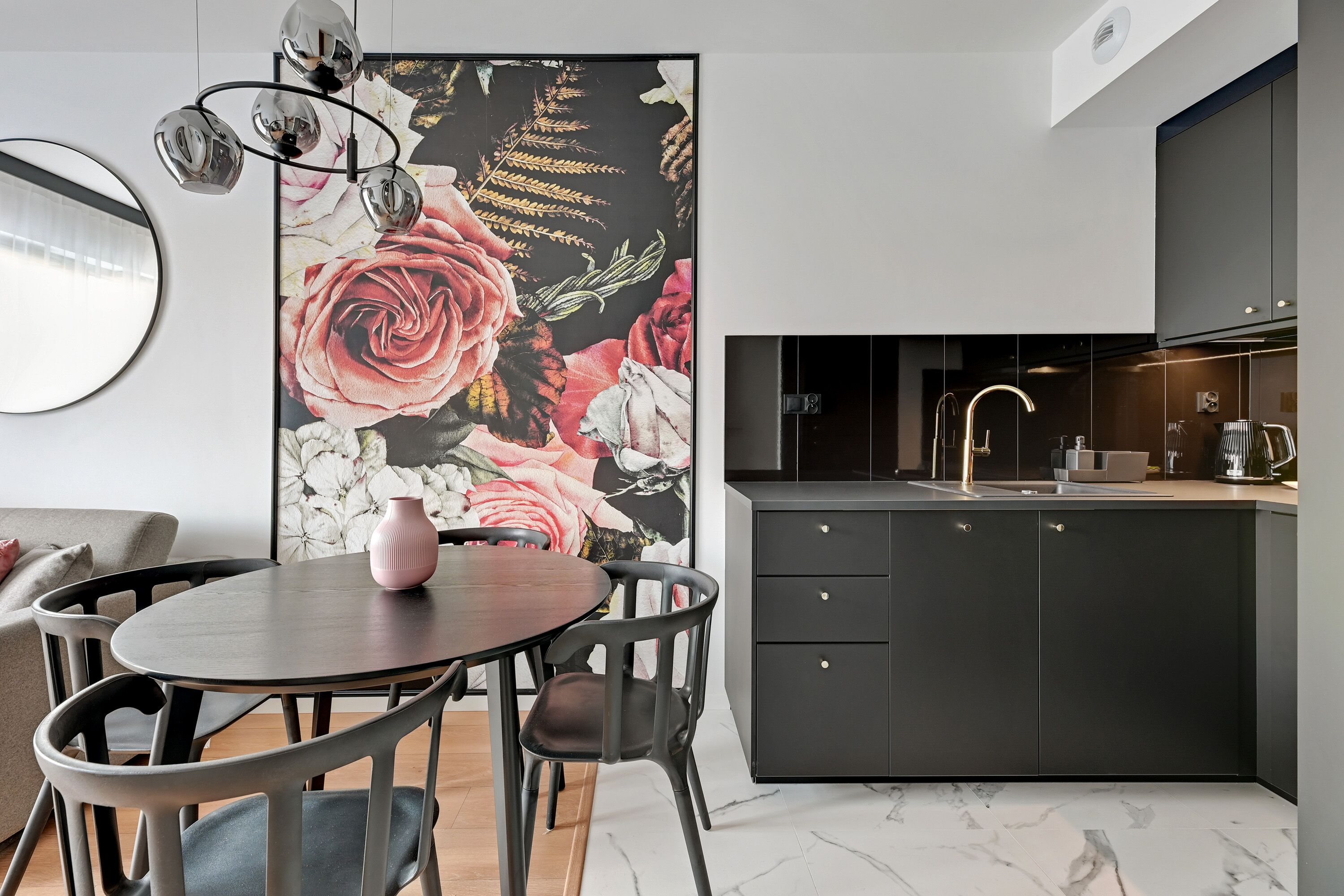 A modern kitchen with dark cabinets, a round dining table, and a floral wall mural.