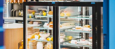 A bakery display case with various baked goods and a selection of bottled beverages in the background.