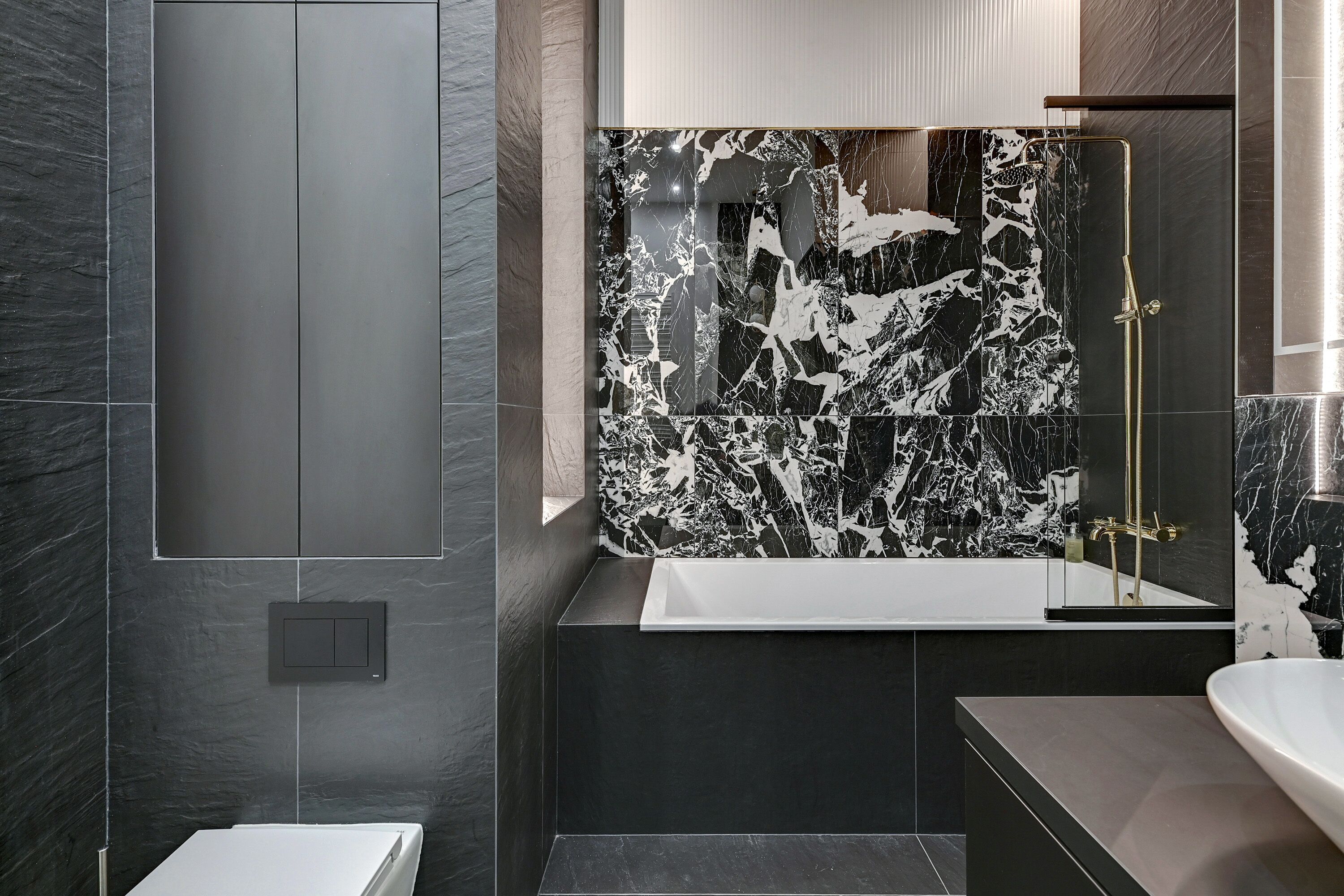 Un baño moderno con pared de mármol, bañera y zona de ducha.