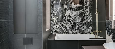 Un baño moderno con pared de mármol, bañera y zona de ducha.