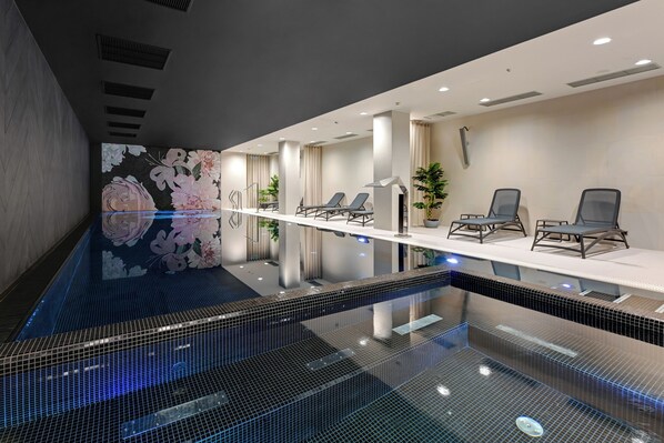 A modern spa area with a long bench, lounge chairs, and a tiled pool. - Grano Apartments Gdańsk Residence (Gdansk)