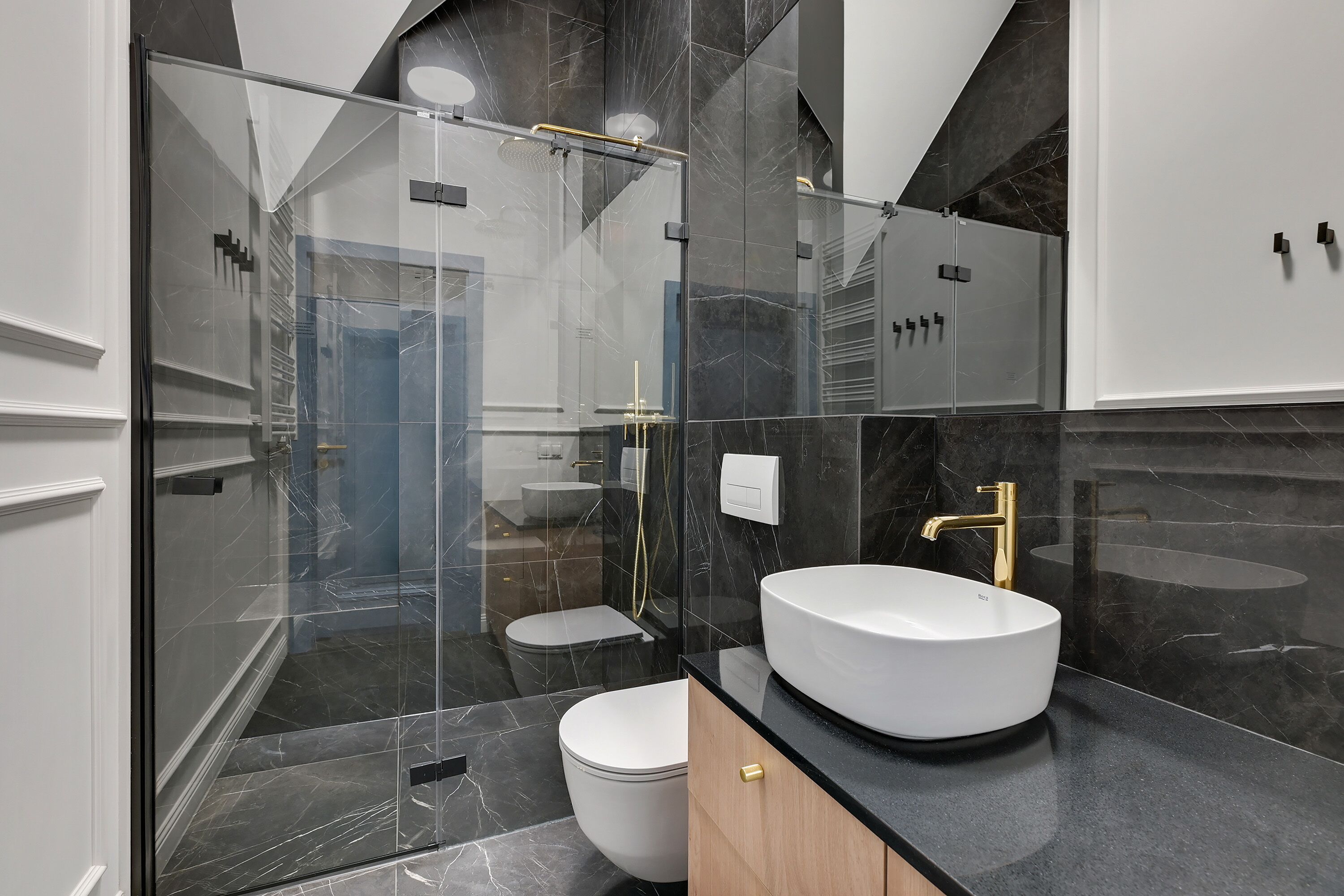 Un baño moderno con ducha de vidrio, lavamanos blanco y retrete.