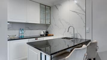 A modern kitchen with marble backsplash, white cabinetry, and a black countertop.