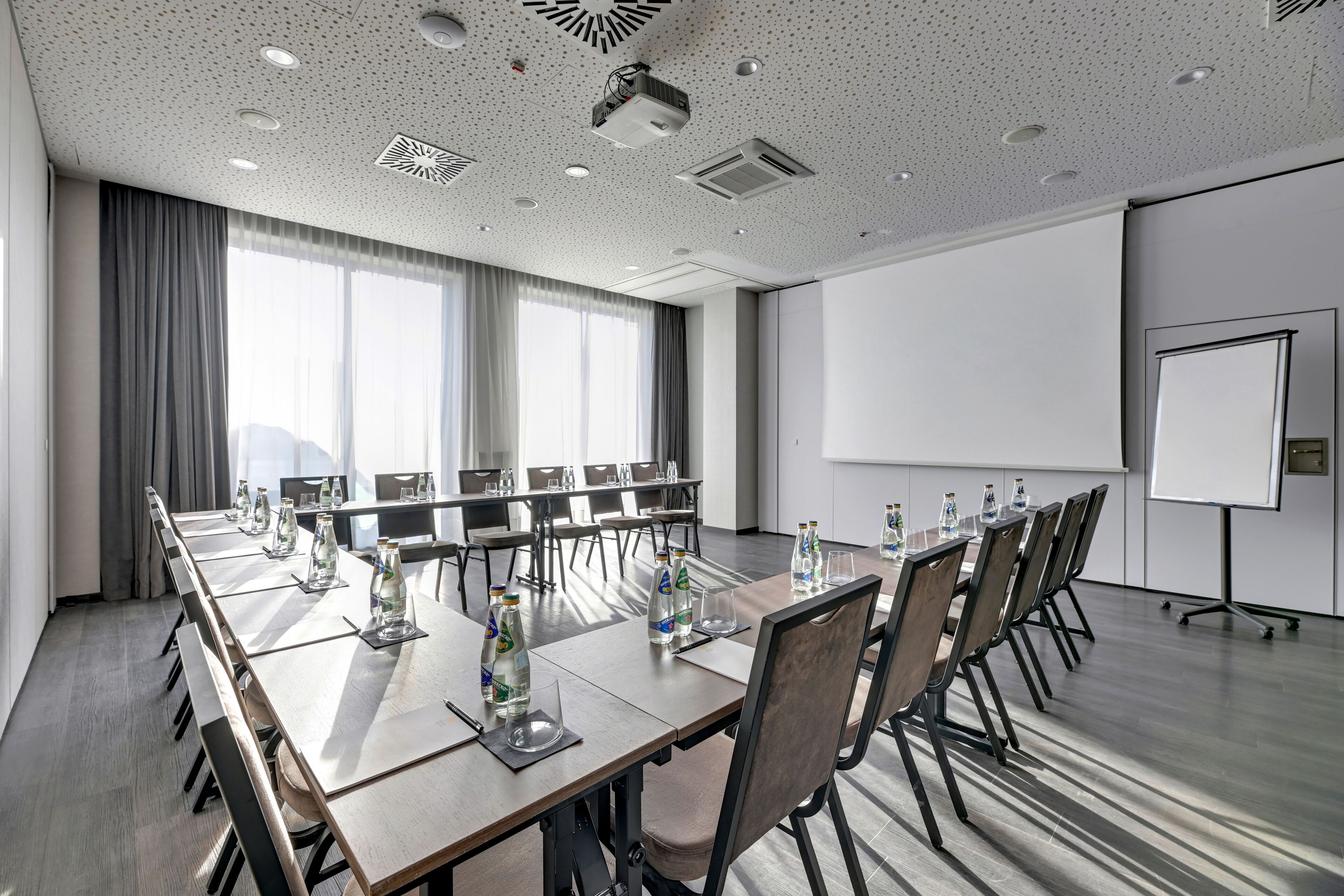 A conference room with a long table, chairs, a projector, and a whiteboard.