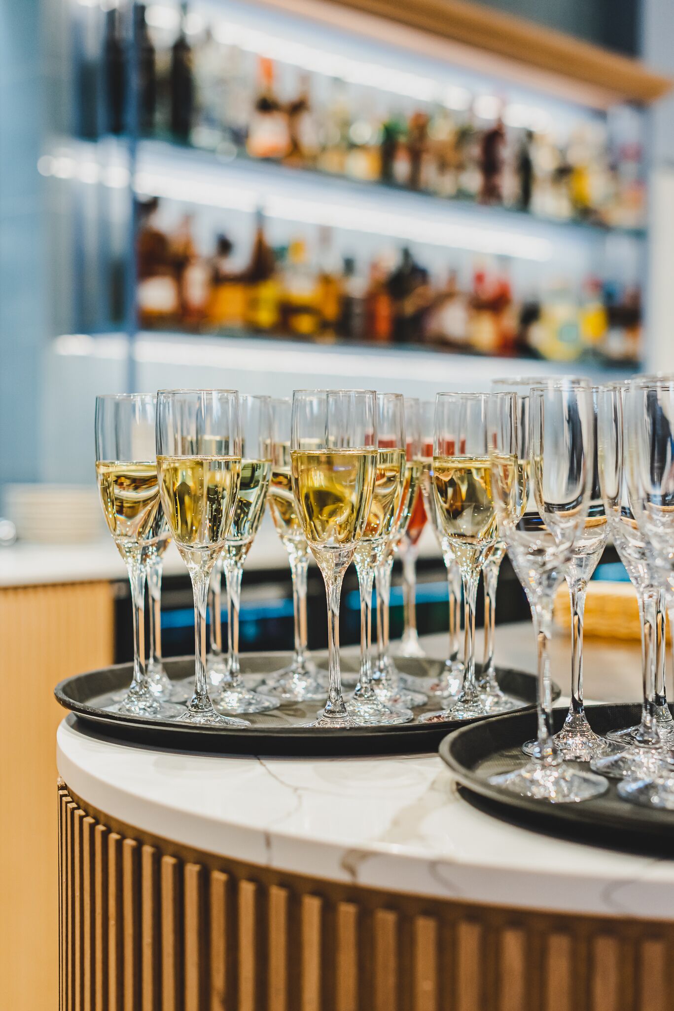 A bar area with multiple glasses of white wine on a tray.
